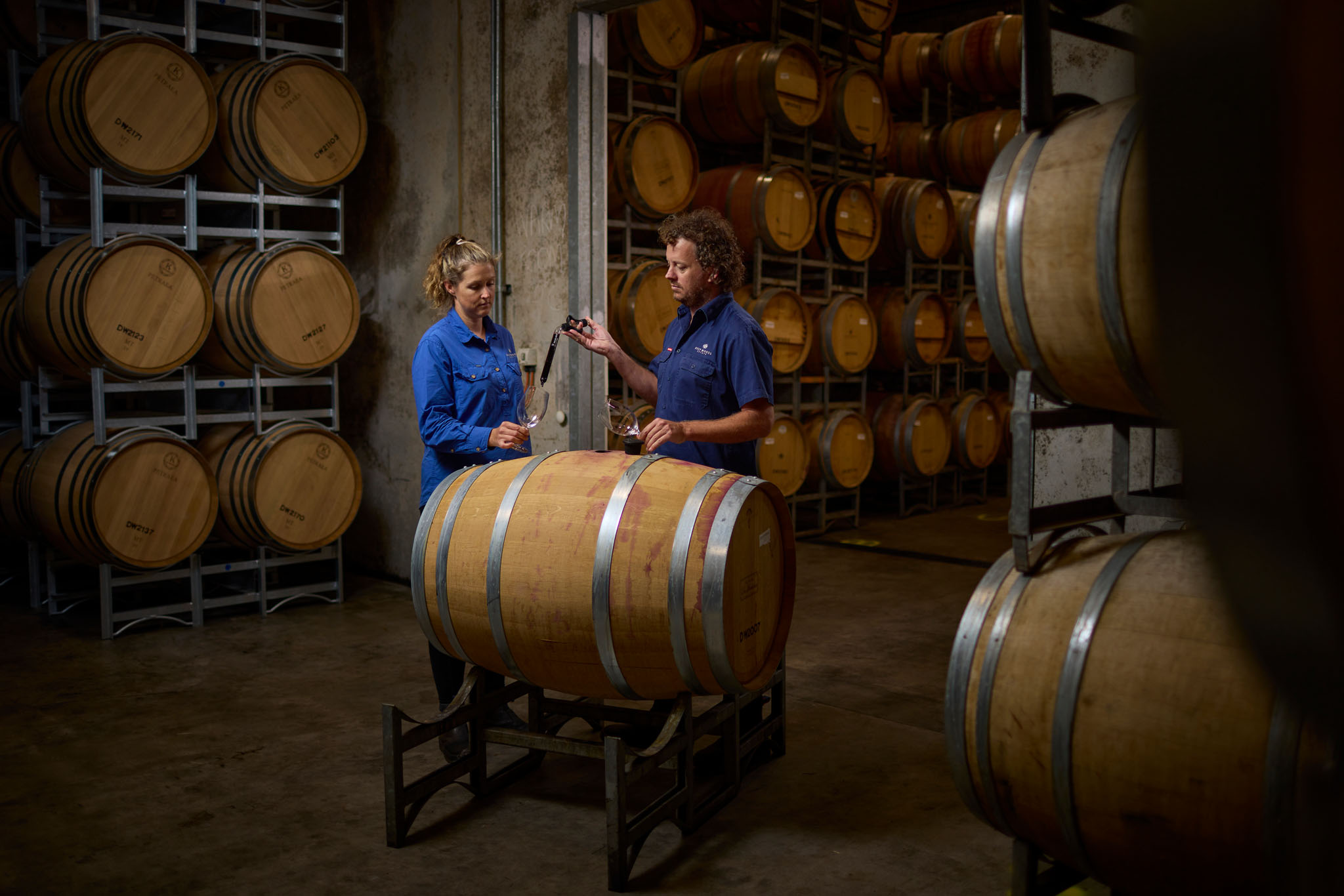 A man and a woman testing the wine from a barrel 